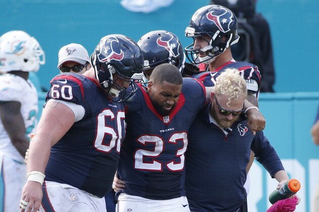 Houston Texans running back Arian Foster (23) is helped off the field by center Ben Jones (60) and an unidentified team member, during the second half of an NFL football game against the Miami Dolphins, Sunday, Oct. 25, 2015 in Miami Gardens, Fla. The Dolphins defeated the Texans 44-26. (AP Photo/Wilfredo Lee)