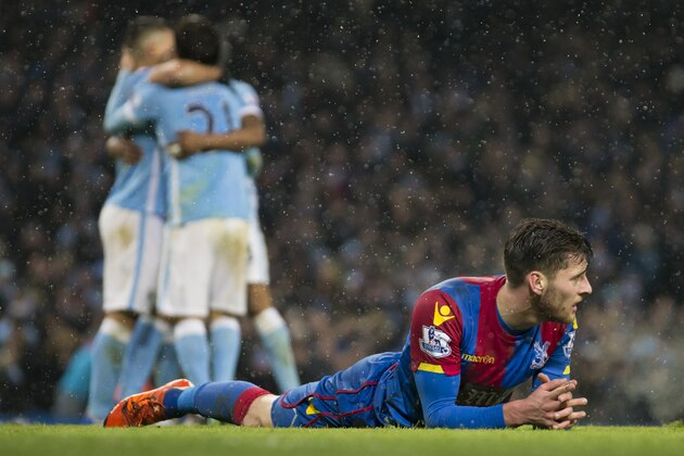 Crystal Palace's Joel Ward lies on the pitch as Manchester City's David Silva, second left, celebrates with teammates after scoring his team's fourth goal during the English Premier League soccer match between Manchester City and Crystal Palace at the Etihad Stadium, Manchester, England, Saturday Jan. 16, 2016. (AP Photo/Jon Super)