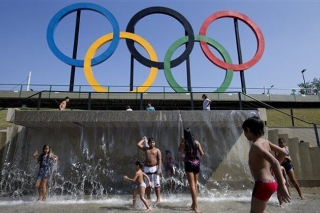 FILE - In this July 28, 2015 file photo, children play in a water fountain next to Olympic rings at Madureira Park in Rio de Janeiro, Brazil. Facing severe budget cuts in almost all aspects of the games, the Rio de Janeiro Olympics will get a boost from Japanese electronics company Panasonic, which has signed on as