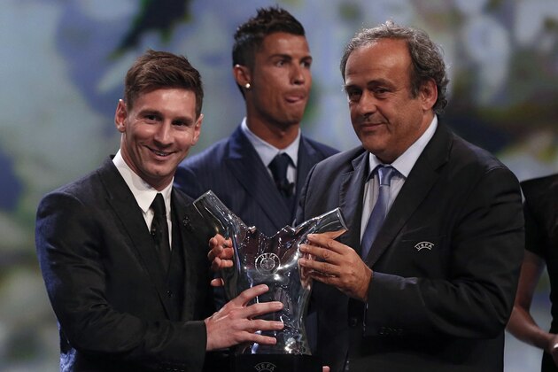 FC Barcelone Argentinian striker Lionel Messi receives from UEFA president Michel Platini (R) the trophy of Best Men's player in Europe next to runner-up Portugal's Cristiano Ronaldo at the end of the UEFA Champions League Group stage draw ceremony, on August 27, 2015 in Monaco. AFP PHOTO / VALERY HACHE        (Photo credit should read VALERY HACHE/AFP/Getty Images)