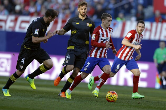 Atletico Madrid's Antoine Griezmann, second right, runs with the ball next to Sevilla's Grzegorz Krychowiak, left, and Fernando Llorente, second left, during a Spanish La Liga soccer match between Atletico Madrid and Sevilla at the Vicente Calderon stadium in Madrid, Sunday, Jan. 24, 2016. The match ended in a 0-0 draw. (AP Photo/Francisco Seco)