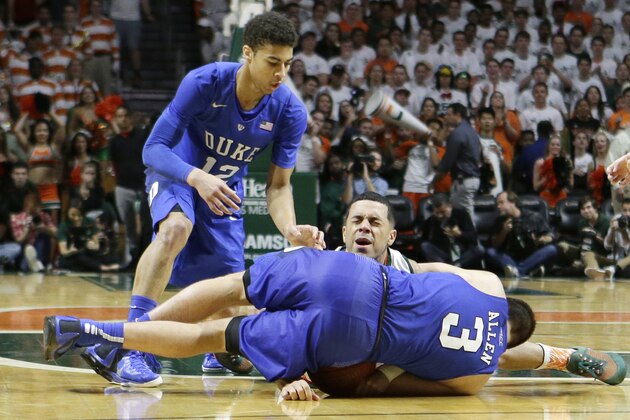 Miami guard Angel Rodriguez (13) grimaces as Duke guard Grayson Allen (3) lands on Rodriguez' arm as they battle for a lose ball  during the second half of an NCAA college basketball game, Monday, Jan. 25, 2016, in Coral Gables, Fla. Miami won 80-69. (AP Photo/Alan Diaz)