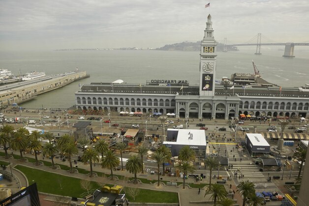 Work continues on the construction of Super Bowl City in front of the Ferry Building, Thursday, Jan. 28, 2016, in San Francisco. The free family-friendly venue opens on Saturday. In the background is the San Francisco-Oakland Bay Bridge. (AP Photo/Eric Risberg)