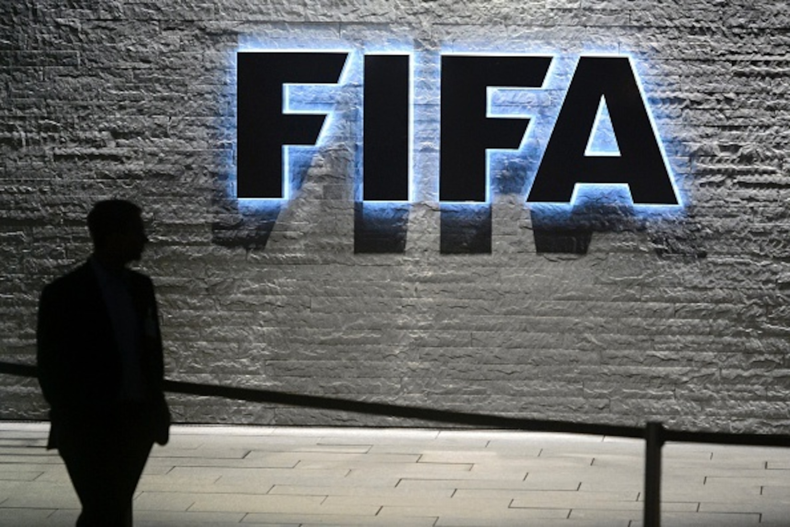 TOPSHOT - A FIFA employee walks past a sign of the FIFA at the headquarters on December 3, 2015 in Zurich. 
The unprecedented corruption scandal engulfing FIFA widened on December 3 with the arrests of two more top officials in another dramatic dawn raid at a luxury hotel in Zurich.   / AFP / FABRICE COFFRINI        (Photo credit should read FABRICE COFFRINI/AFP/Getty Images)