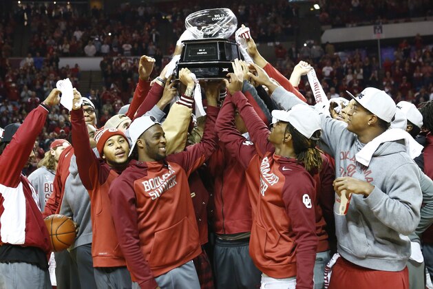 The Oklahoma Football team holds up their 2015 Big 12 Trophy during halftime of an NCAA college basketball game against Wisconsin in Norman, Okla., Sunday, Nov. 29, 2015. (AP Photo/Alonzo Adams)