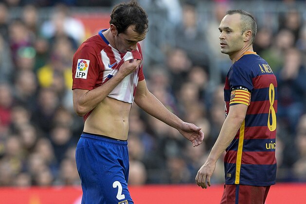 Atletico Madrid's Uruguayan defender Diego Godin (L) passes by Barcelona's midfielder Andres Iniesta as he leaves the pitch after being sent off by referee during the Spanish league football match FC Barcelona vs Club Atletico de Madrid at the Camp Nou stadium in Barcelona on January 30, 2016. Barcelona won 2-1.   AFP PHOTO/ JOSEP LAGO / AFP / JOSEP LAGO        (Photo credit should read JOSEP LAGO/AFP/Getty Images)
