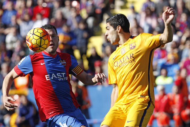 Barcelona's Luis Suarez, right,  duels for the ball with Levante's David Navarro, during a Spanish La Liga soccer match between Levante and Barcelona,  at the Ciutat de Valencia stadium in Valencia, Spain, Sunday, Feb. 7, 2016. (AP Photo/Alberto Saiz)