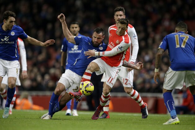 Arsenal's Mesut Ozil, 11, competes for the ball with Leicester City's Marcin Wasilewski during the English Premier League soccer match between Arsenal and Leicester City at the Emirates Stadium in London, Tuesday, Feb. 10, 2015.  (AP Photo/Matt Dunham)