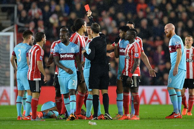 Referee Mark Clattenburg (C) shows Southampton's Kenyan midfielder Victor Wanyama (3L) the red card for a challenge on West Ham United's French midfielder Dimitri Payet (laying on pitch) during the English Premier League football match between Southampton and West Ham United at St Mary's Stadium in Southampton, southern England on February 6, 2016. / AFP / GLYN KIRK / RESTRICTED TO EDITORIAL USE. No use with unauthorized audio, video, data, fixture lists, club/league logos or 'live' services. Online in-match use limited to 75 images, no video emulation. No use in betting, games or single club/league/player publications.  /         (Photo credit should read GLYN KIRK/AFP/Getty Images)