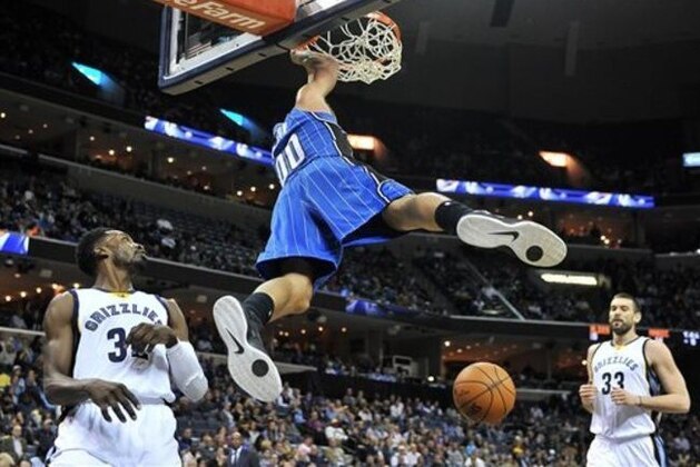 Orlando Magic forward Aaron Gordon (00) hangs from the rim after dunking the ball between Memphis Grizzlies forward Jeff Green (32) and center Marc Gasol (33) in the first half of an NBA basketball game Monday, Jan. 26, 2015, in Memphis, Tenn. (AP Photo/Brandon Dill)