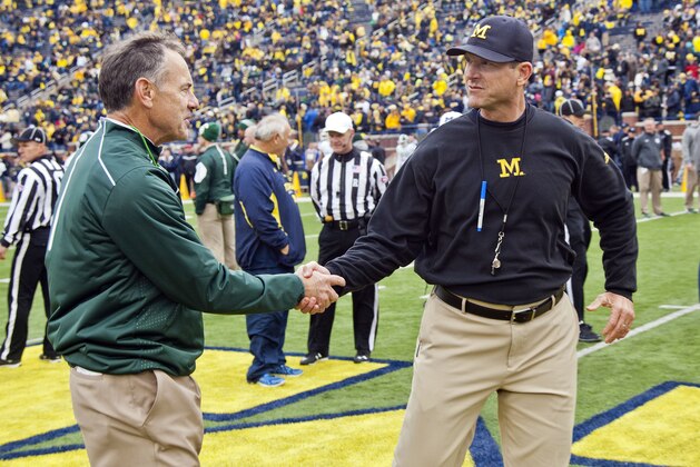 Michigan State head coach Mark Dantonio shakes hands with Michigan head coach Jim Harbaugh on the Michigan Stadium field before an NCAA college football game in Ann Arbor, Mich., Saturday, Oct. 17, 2015. (AP Photo/Tony Ding)