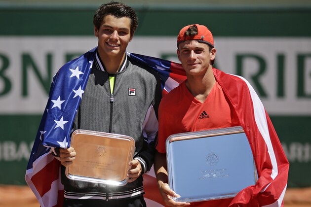 Tommy Paul of the U.S., right, holds the trophy after winning the boys final match of the French Open tennis tournament against Taylor Harry Fritz of the U.S., left, in three sets 7-6, 2-6, 6-2, at the Roland Garros stadium, in Paris, France, Saturday, June 6, 2015. (AP Photo/Thibault Camus)