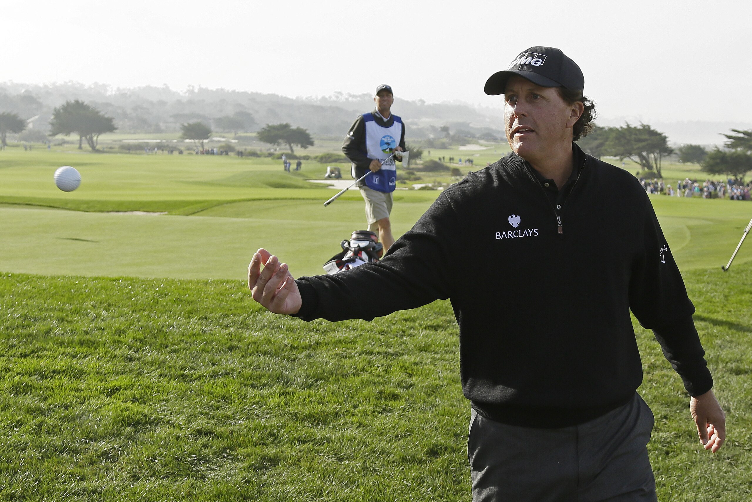 Phil Mickelson tosses his ball to the gallery after putting on the sixth green of the Monterey Peninsula Country Club Shore Course during the second round of the AT&T Pebble Beach National Pro-Am golf tournament Friday, Feb. 12, 2016, in Pebble Beach, Calif. (AP Photo/Eric Risberg)