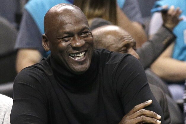 Charlotte Hornets owner Michael Jordan smiles as he watches his team in the first half of an NBA basketball game against the Detroit Pistons in Charlotte, N.C., Monday, Dec. 7, 2015. (AP Photo/Chuck Burton)