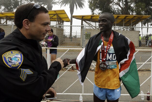 Men's' third-place finisher Daniel Limo celebrates with a Santa Monica police officer after the Los Angeles Marathon, Sunday, Feb. 14, 2016, in Santa Monica, Calif. (AP Photo/Chris Carlson)