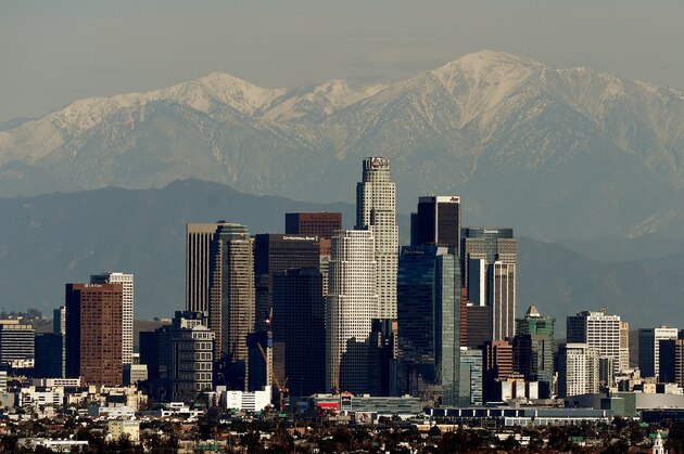 The Los Angeles city skyline stands in front of the snow covered San Gabriel Mountains after a snowstorm hit the region on December 31, 2014.  Two people were killed as storm-driven winds blasted beaches and dozens of motorists were stranded overnight on mountain roads in Los Angeles and Orange counties.                  AFP PHOTO/MARK RALSTON        (Photo credit should read MARK RALSTON/AFP/Getty Images)