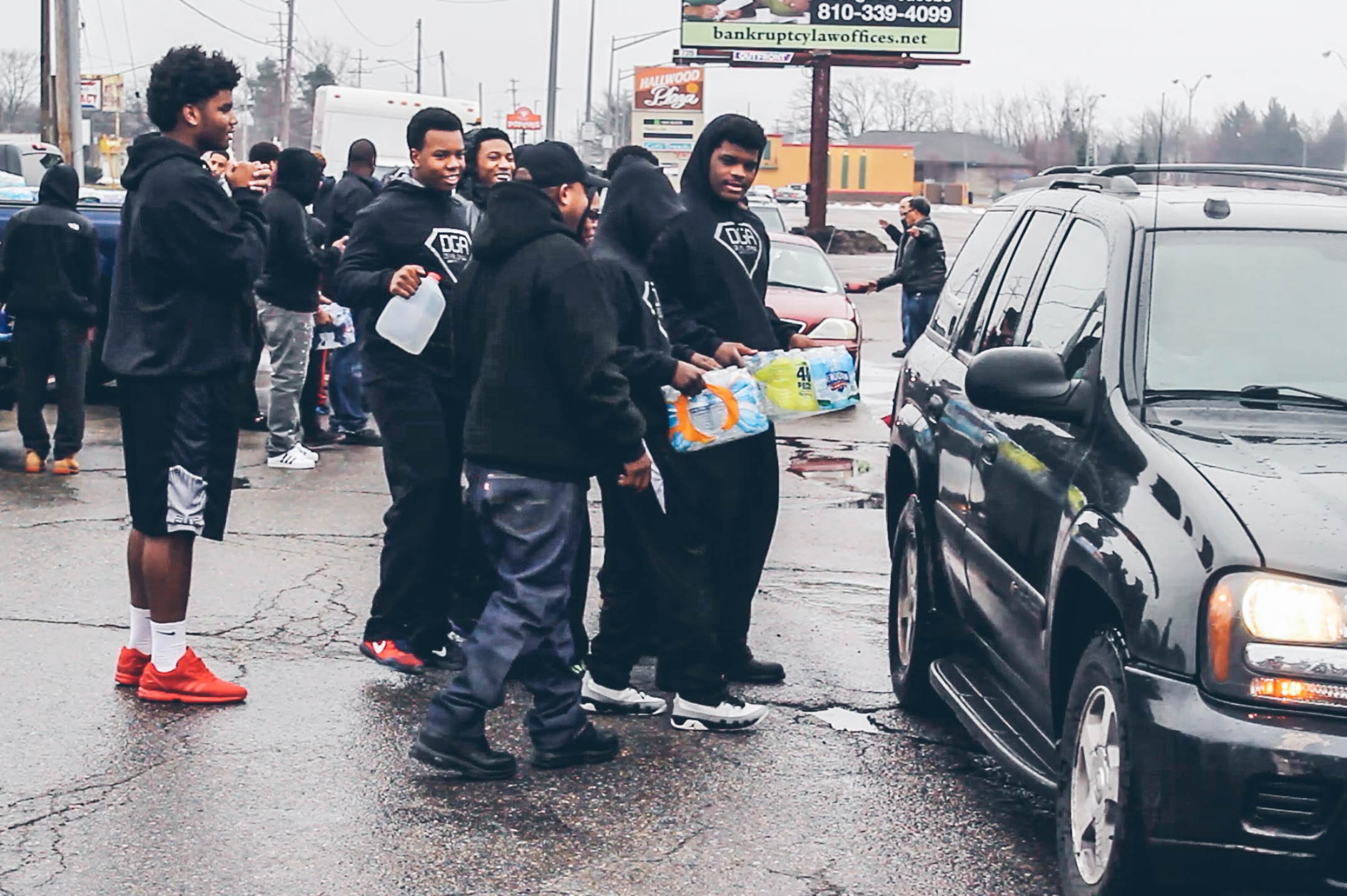 Top Michigan recruits such 4-star OL JaRaymond Hall (left, in shorts) and 2018 OL Marquan McCall (far right, with water in hand) were among a group of athletes who helped deliver water to residents in Flint.