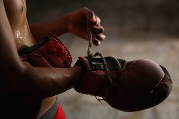 HAVANA, CUBA - MAY 09:  Jaime Poradius, 16-years-old, takes off his boxing gloves after a training session at the Salvador Allende Sports Complex on May 9, 2015 in Alamar, Cuba.  Alamar is a suburb of Havana. The town, which is about 30 minutes east of Havana, was built in the 1970Õs when the city center to supply much need housing to the people of Cuba. The gym where kids work out here is run by a coach Lazaro Goyalo Perez Quintana. The gym is not much of a gym, but rather a small room under a now-empty Olympic size swimming pool. The room has one light, one punching bag, and a couple of bags filled with sand pinned up against the wall for the boxers to train with.  Although baseball is known as the national sport of Cuba, boxing in the sport where they have achieved the greatest dominance at the Olympic Games. Since the 1968 Games, Cuba has won a total of 53 medals, and 33 of those have been gold medals Ñ no other country is even close to those numbers.  Boxing starts as early as eight-years old for boys in