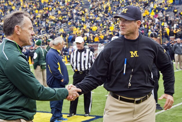 Michigan State head coach Mark Dantonio shakes hands with Michigan head coach Jim Harbaugh on the Michigan Stadium field before an NCAA college football game in Ann Arbor, Mich., Saturday, Oct. 17, 2015. (AP Photo/Tony Ding)