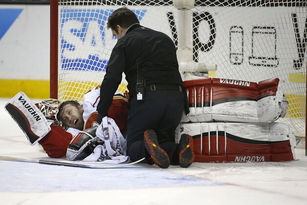 Calgary Flames goalie Karri Ramo is checked on by a trainer after Ramo's collision with San Jose Sharks' Joonas Donskoi during the third period of an NHL hockey game in San Jose, Calif., Thursday, Feb. 11, 2016. The Flames defeated the Sharks 6-5 in a shootout. (AP Photo/Tony Avelar)