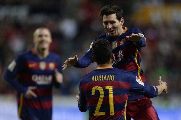 Barcelona's Argentinian forward Lionel Messi celebrates with teammate Brazilian defender Adriano after scoring a goal during the Spanish league football match Real Sporting de Gijon vs FC Barcelona at El Molinon stadium in Gijon on February 17, 2016. / AFP / MIGUEL RIOPA        (Photo credit should read MIGUEL RIOPA/AFP/Getty Images)