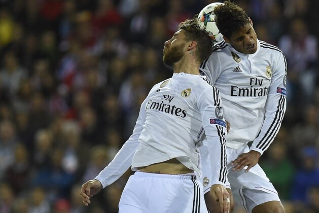 Real Madrid's defender Sergio Ramos (L) and Real Madrid's French defender Raphael Varane (R) jump for the ball during the UEFA Champions League quarter final first leg football match Atletico de Madrid vs Real Madrid CF at the Vicente Calderon stadium in Madrid on April 14, 2015.      AFP PHOTO / PIERRE-PHILIPPE MARCOU        (Photo credit should read PIERRE-PHILIPPE MARCOU/AFP/Getty Images)
