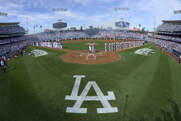 In this photo taken with a fisheye lens, Los Angeles Dodgers manager Don Mattingly, center left, and St. Louis Cardinals manager Mike Matheny hug at the plate as their teams line up on the baselines before Game 1 of baseball's NL Division Series in Los Angeles, Friday, Oct. 3, 2014. (AP Photo/Mark J. Terrill)