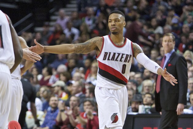 Portland Trail Blazers guard Damian Lillard high-fives a teammate after scoring against the Golden State Warriors during the second half of an NBA basketball game in Portland, Ore., Friday, Feb. 19, 2016. Portland won 137-105. (AP Photo/Craig Mitchelldyer)