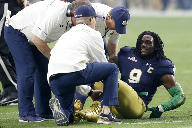 Notre Dame linebacker Jaylon Smith (9) is attended to after being injured against Ohio State during the first half of the Fiesta Bowl NCAA College football game, Friday, Jan. 1, 2016, in Glendale, Ariz.  (AP Photo/Rick Scuteri)