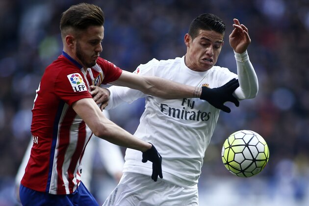 Atletico's Saul, left, duels for the ball with Real Madrid’s James during a Spanish La Liga soccer match between Real Madrid and Atletico Madrid at the Santiago Bernabeu stadium in Madrid, Spain, Saturday Feb. 27, 2016. (AP Photo/Oscar del Pozo)