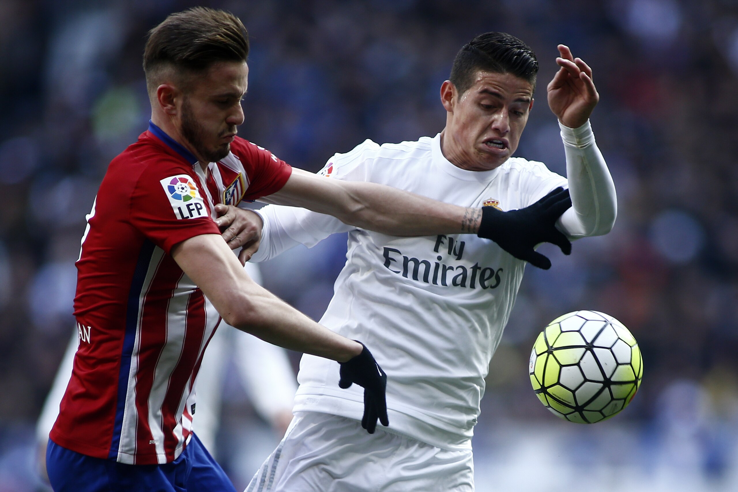 Atletico's Saul, left, duels for the ball with Real Madrid’s James during a Spanish La Liga soccer match between Real Madrid and Atletico Madrid at the Santiago Bernabeu stadium in Madrid, Spain, Saturday Feb. 27, 2016. (AP Photo/Oscar del Pozo)
