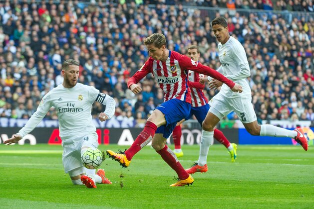 Real Madrid's defender Sergio Ramos (L) and Real Madrid's French defender Raphael Varane (R) vies with Atletico Madrid's forward Fernando Torres during the Spanish league football match Real Madrid CF vs Club Atletico de Madrid at the Santiago Bernabeu stadium in Madrid on February 27, 2016. / AFP / CURTO DE LA TORRE        (Photo credit should read CURTO DE LA TORRE/AFP/Getty Images)