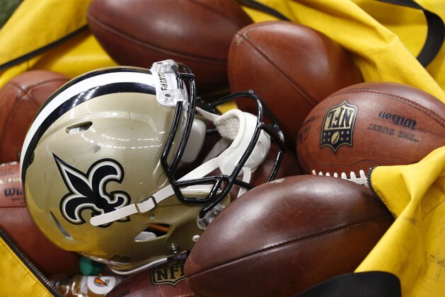 A New Orleans Saints helmet sits amongst Wilson footballs in the second half of an NFL football game in New Orleans, Sunday, Oct. 4, 2015. (AP Photo/Jonathan Bachman)