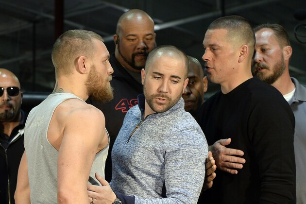 TORRANCE, CA - FEBRUARY 24:  UFC featherweight champion Conor McGregor (L) and lightweight contender Nate Diaz (R) are held apart by Dave Sholler (C), UFC vice president of public relations, after a news conference at UFC Gym February 24, 2016, in Torrance, California.  (Photo by Kevork Djansezian/Getty Images)