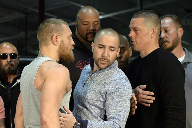 TORRANCE, CA - FEBRUARY 24:  UFC featherweight champion Conor McGregor (L) and lightweight contender Nate Diaz (R) are held apart by Dave Sholler (C), UFC vice president of public relations, after a news conference at UFC Gym February 24, 2016, in Torrance, California.  (Photo by Kevork Djansezian/Getty Images)