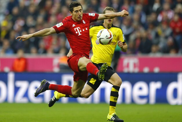 Bayern's Robert Lewandowski, foreground, challenges for the ball to score his side's third goal during the German Bundesliga soccer match between FC Bayern Munich and Borussia Dortmund at the Allianz Arena stadium in Munich, Germany, Sunday, Oct. 4, 2015. (AP Photo/Matthias Schrader)