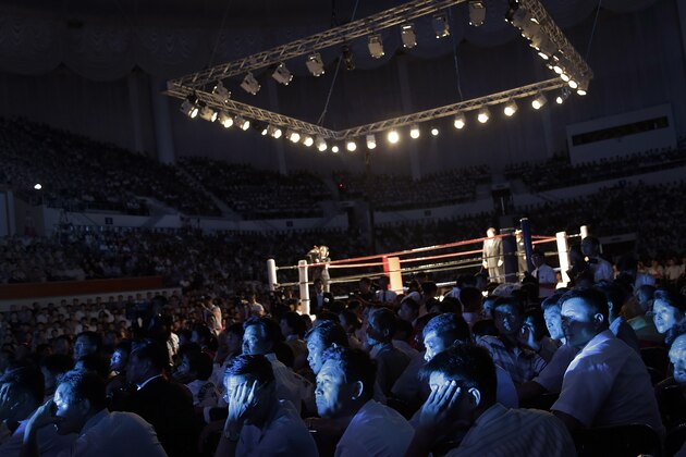 The faces of North Koreans are illuminated by stage lighting as they watch pro wrestlers enter the arena, Saturday, Aug. 30, 2014 in Pyongyang, North Korea. North Koreans got their first look at pro wrestling in about 20-years on Saturday when former NFL lineman Bob