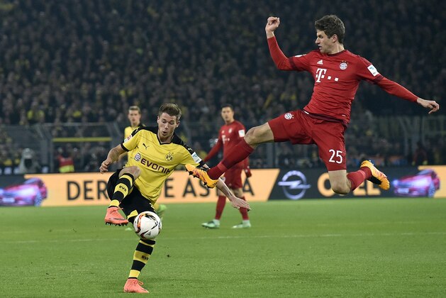 Dortmund's Julian Weigl, left, and Bayern's Thomas Mueller challenge for the ball during the German Bundesliga soccer match between Borussia Dortmund and Bayern Munich, in Dortmund, Germany, Saturday, March 5, 2016. (AP Photo/Martin Meissner)