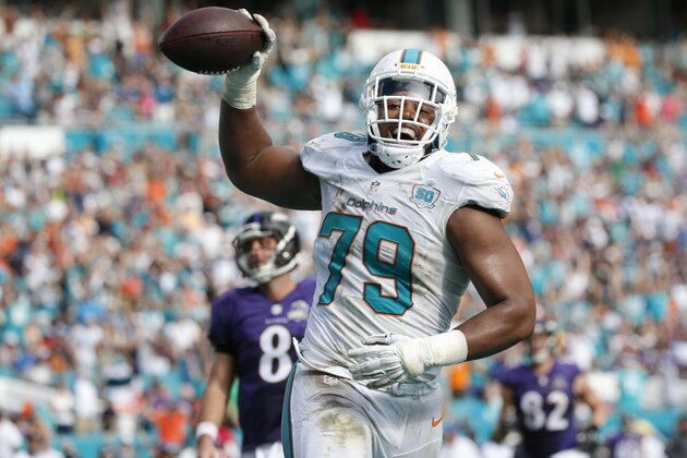 Miami Dolphins defensive end Derrick Shelby (79) smiles as he scores a touchdown after intercepting the ball during the first half of an NFL football game against the Baltimore Ravens, Sunday, Dec. 6, 2015, in Miami Gardens, Fla.  (AP Photo/Wilfredo Lee)