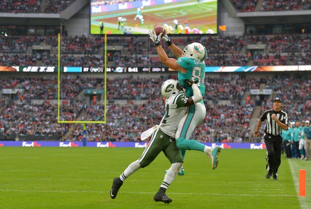 Oct 4, 2015; London, United Kingdom; Miami Dolphins tight end Jordan Cameron (84) is defended by New York Jets cornerback Dion Bailey (34) in Game 12 of the NFL International Series at Wembley Stadium. The Jets defeated the Dolphins 27-14. Mandatory Credit: Kirby Lee-USA TODAY Sports