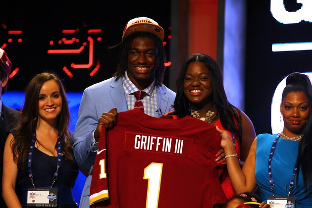 NEW YORK, NY - APRIL 26:  Robert Griffin III from Baylor holds up a jersey as he poses on stage with family including his fiancee Rebecca Liddicoat (L of Griffin) after Griffin was selected #2 overall by the Washington Redskins in the first round of the 2012 NFL Draft at Radio City Music Hall on April 26, 2012 in New York City.  (Photo by Al Bello/Getty Images)