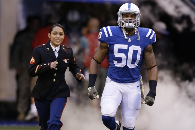 Indianapolis Colts' Jerrell Freeman (50) runs onto the field with a Military person before an NFL football game Sunday, Nov. 8, 2015, Indianapolis. (AP Photo/Michael Conroy)