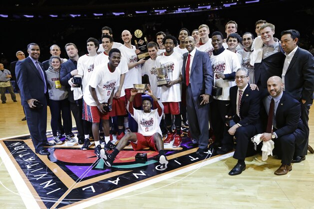 Stanford coach Johnny Dawkins, with red tie, poses for photographs with his team and the tournament trophy after the championship game against Miami at the NIT college basketball tournament Thursday, April 2, 2015, in New York. Stanford won 66-64 in overtime. (AP Photo/Frank Franklin II)