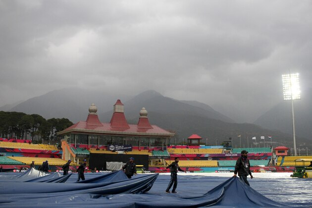 Indian groundstaff cover the wicket as rain falls ahead of the World T20 cricket tournament qualifying match between Oman and The Netherlands at The Himachal Pradesh Cricket Association Stadium in Dharamsala on March 11, 2016.  / AFP / STR        (Photo credit should read STR/AFP/Getty Images)