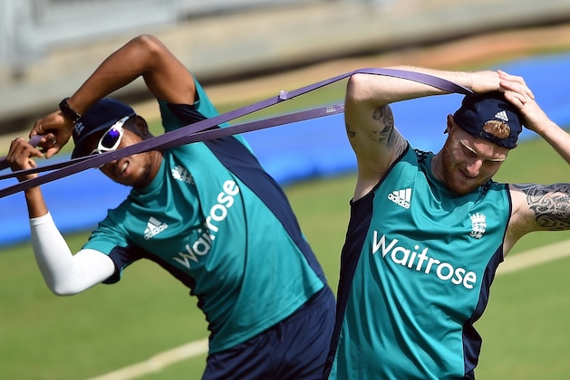 TOPSHOT - England's Ben Stokes(R)and teammate Chris Jordan stretch while warming up prior to a training session at The Wankhede Stadium in Mumbai on March 11, 2016. 
England play their first match of the World T20 cricket tournament against the West Indies on March 16 in Mumbai. / AFP / PUNIT PARANJPE        (Photo credit should read PUNIT PARANJPE/AFP/Getty Images)