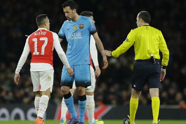 Arsenal's Alexis Sanchez, left speaks to Barcelona's Sergio Busquets  following a foul during the Champions League round of 16 first leg soccer match between Arsenal and Barcelona at the Emirates stadium London, Tuesday, Feb. 23, 2016. (AP Photo/Matt Dunham)