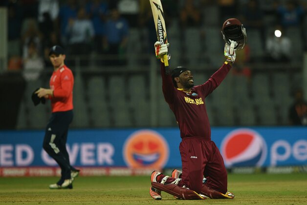 West Indies's Chris Gayle celebrates after scoring his century (100runs) as England's captain Eoin Morgan walks past during the World T20 cricket tournament match between England and West Indies at The Wankhede Cricket Stadium in Mumbai on March 16, 2016.
 / AFP / INDRANIL MUKHERJEE        (Photo credit should read INDRANIL MUKHERJEE/AFP/Getty Images)