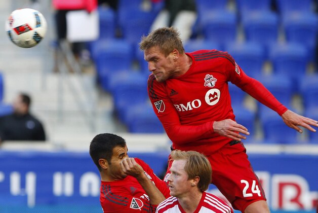 Mar 6, 2016; Harrison, NJ, USA; Toronto FC defender Damien Perquis (24) heads the ball away from New York Red Bulls midfielder Dax McCarty (11) during second half at Red Bull Arena.The Toronto FC defeated the New York Red Bulls 2-0. Mandatory Credit: Noah K. Murray-USA TODAY Sports