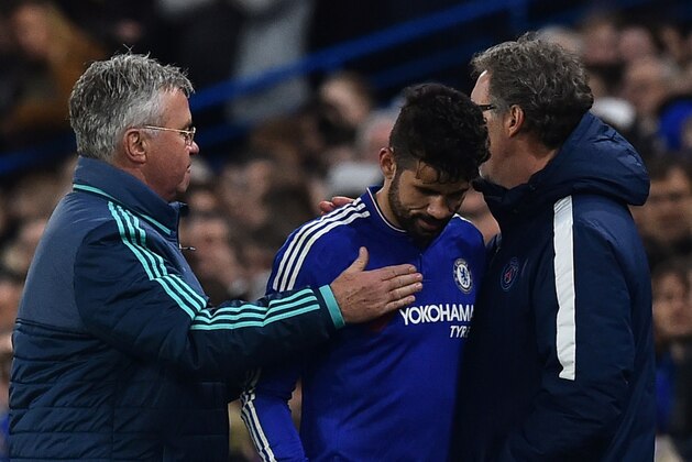 Chelsea's Brazilian-born Spanish striker Diego Costa gets pats from Chelsea's Dutch interim manager Guus Hiddink (L) and Paris Saint-Germain's French head coach Laurent Blanc (R) as he leaves the pitch injured during the UEFA Champions League round of 16 second leg football match between Chelsea and Paris Saint-Germain (PSG) at Stamford Bridge in London on March 9, 2016.  / AFP / BEN STANSALL        (Photo credit should read BEN STANSALL/AFP/Getty Images)