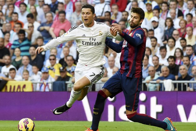 Real Madrid's Portuguese forward Cristiano Ronaldo (L) vies with Barcelona's defender Gerard Pique during the Spanish league 'Clasico' football match Real Madrid CF vs FC Barcelona at the Santiago Bernabeu stadium in Madrid on October 25, 2014.  AFP PHOTO / GERARD JULIEN        (Photo credit should read GERARD JULIEN/AFP/Getty Images)